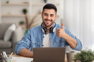 Smiling israeli man working on laptop showing thumbs up